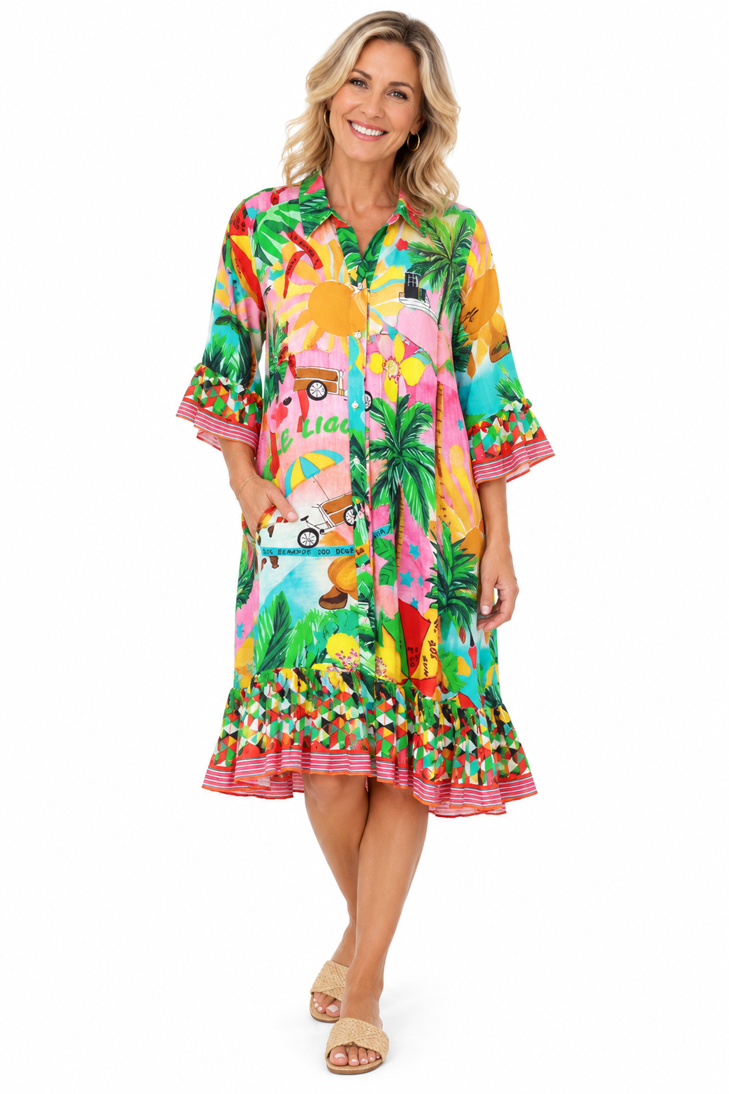 A woman modeling a vibrant tropical-themed midi dress with a colorful print of palm trees, beach umbrellas, and a retro car, set against a plain white background.