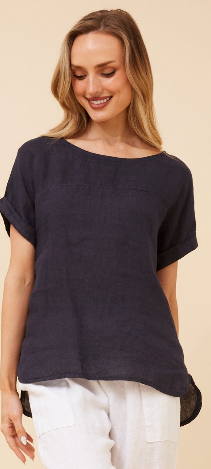A woman wearing a dark navy blue short-sleeve top and white pants, shown in a mobile app screenshot with a small inset of the full outfit on the right.